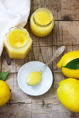Homemade lemon curd with jars and lemons on wooden background. Rustic style.