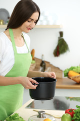 Beautiful Hispanic woman cooking soup in kitchen. Healthy meal and householding concepts