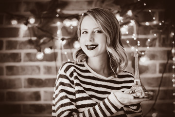 Portrait of a young cozy woman with Eiffel tower and Christmas lights on background