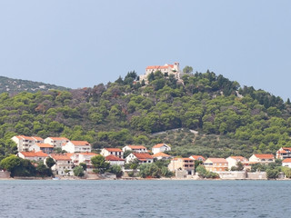 Pasman, Croatia, Europe - 7 9 2018: Embankment of a small Croatian town in the Adriatic Sea. Sailing yacht on the background of the Dalmatian Riviera. Tourism and architecture of the Mediterranean.