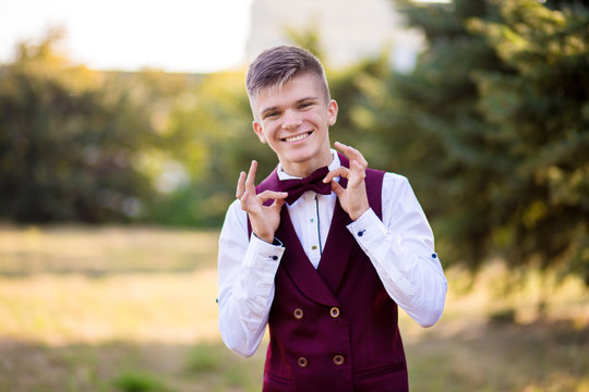 Handsome young waiter in red uniform look at camera. Employee recruitment concept