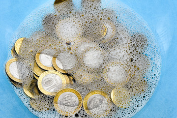 Money-laundering. Coin laundering in soapy water. The concept of tax evasion.