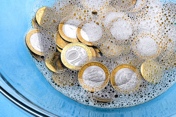 Money-laundering. Coin laundering in soapy water. The concept of tax evasion.