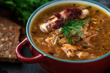 Soup in a plate on a dark wooden background. Russian cabbage soup.