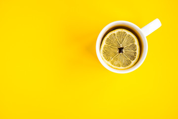 Mug of hot tea with lemon on yellow background. Catarrhal disease. Flu season.