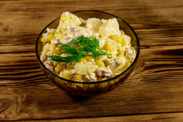Festive salad with chicken breast, sweet corn, canned pineapple, cheese and mayonnaise on wooden table