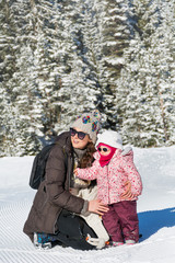 Fototapeta na wymiar Happy Family Mother and Child Daughter Having Fun, Playing in a Winter Snowy Mountain .Parenting Concept 