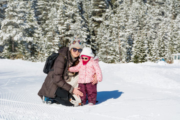 Fototapeta na wymiar Happy Family Mother and Child Daughter Having Fun, Playing in a Winter Snowy Mountain .Parenting Concept 