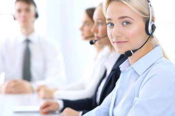 Call center. Group of operators at work. Focus at blonde business woman in headset
