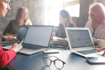 Employees discuss business issues in the office. A group of businesswomen talking at a table in the office