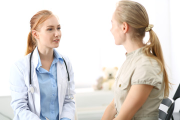 Doctor and patient having a pleasure talk while sitting at the chairs at hospital office. Healthcare and medicine concept