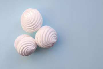 White marshmallows on blue background. Flat lay, copy space