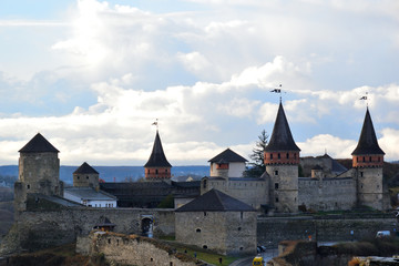 View of the medieval fortress Kamenets-Podolsk. Gray stone walls with towers on a background of clouds