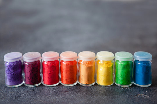 Bright colourful powdered pigments in glass bottles for Indian holi festival on dark slate background, copy space