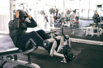 A young man of Asian sit-ups, abdominal workout bench in a gym.