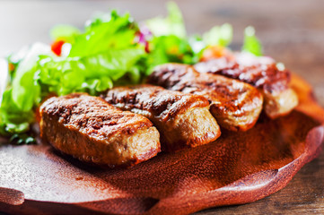 roasted sausages and various fresh mix salad leaves with tomato in plate on wooden table background
