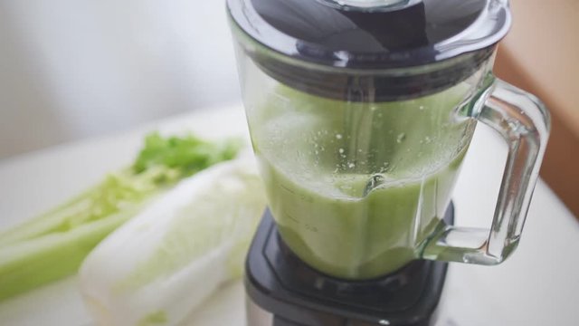 Close up of man cooking healthy detox smoothie with fresh green vegetables