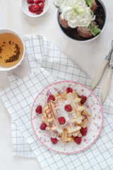 Flat lay breakfast with fresh waffles and raspberries on the table