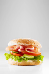 Salami sandwich made from bun, sliced ham and fresh letttuce, tomato and cheese. Healthy breakfast. Copy space 