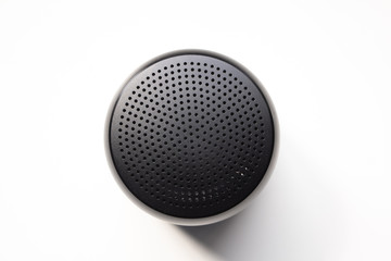 Top View of a Round Portable Black Wireless Speaker, Isolated on White Background, Showing Dotted Grille Holes.