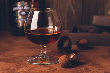 A glass of strong alcoholic drink brandy or brandy and a box of chocolates on a dark background. Copy space.