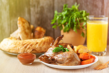 Roasted chicken, potatoes and vegetables on dark plate. Side view