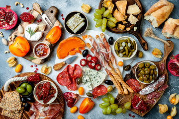 Fototapeta na wymiar Appetizers table with antipasti snacks. Authentic traditional spanish tapas set, cheese and meat platter over grey concrete background. Top view