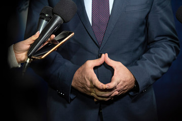 Journalist ask questions to politician with clasped hands during the press conference