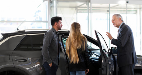 Car dealer showing a car to a couple