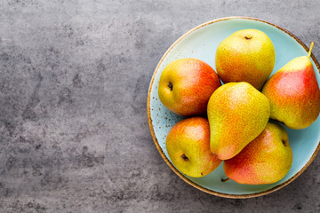 Fresh bio pear with leaves on the plate. Gray stone table.