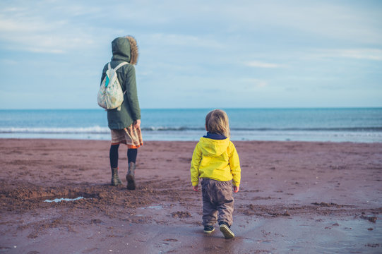 Toddler on the beach with his mother in winter