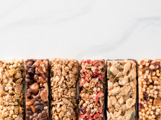 Granola bar with copy space. Set of different granola bars on white marble table. Shallow DOF. Top view or flat lay.