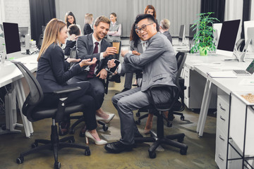 smiling young business people drinking coffee and talking during coffee break