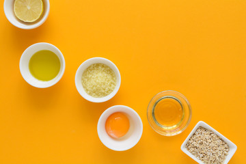 Obraz na płótnie Canvas Fresh ingredients for homemade effective acne remedies on yellow background. Honey, sea salt, egg yolk, olive oil, oat, lemon and aloe. Flat lay. Copy space