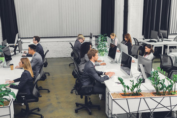 high angle view of professional young business people working with desktop computers in open space...