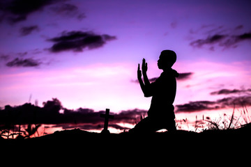 Fototapeta na wymiar Boy praying to god with cross, christian silhouette concept.