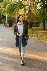 Fototapeta premium Smiling young asian woman wearing coat walking