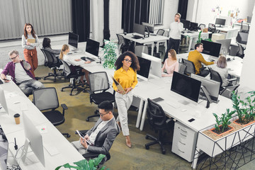 high angle view of multiracial young business people working with computers and documents in open...