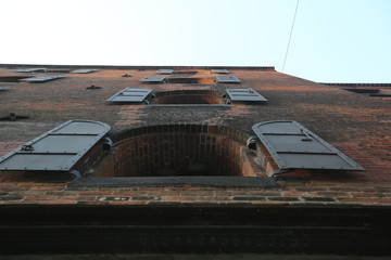 Bottom view of the building of brick which is connected by concrete with windows