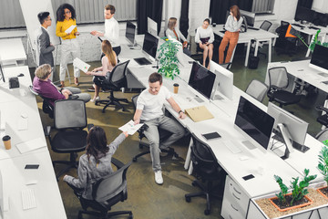 high angle view of professional young colleagues working with papers and computers in open space...