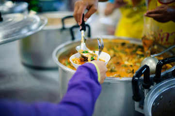 The hands of the poor bring the container to fill the food to bring back to the accommodation.