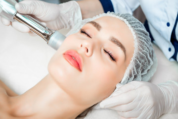 Obraz na płótnie Canvas The doctor cosmetologist makes the Rejuvenating facial injections procedure for tightening and smoothing wrinkles on the face skin of a beautiful, young woman in a beauty salon