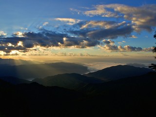 A wide landscape of dawn golden light inside the cloud with blue sky shine over the forest, mountain and the fog. Just an amazing moment