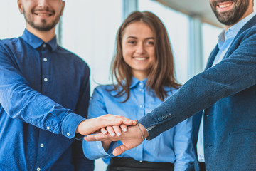 Three business people placing a contract put a hand on hand.