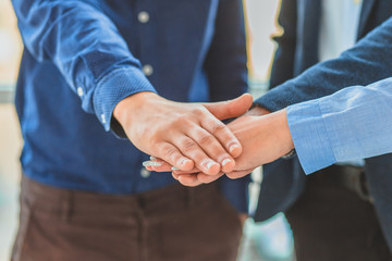 Three business people placing a contract put a hand on hand.