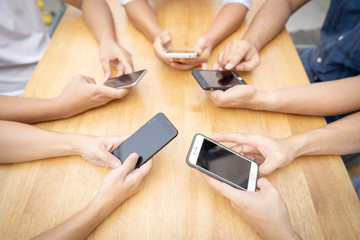 group of young man or friends playing online application game in modern touch screen mobile on wood table.