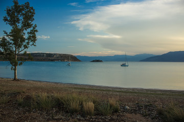 evening sea bay peaceful scenic landscape empty sand coast shoreline and fishing boats on calm water surface 