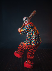 Scary bloody clown reaches out baseball bat