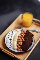 Closeup of healthy Breakfast plate with yogurt with chocolate chips, banana, rye bread and hazelnut on the kitchen table