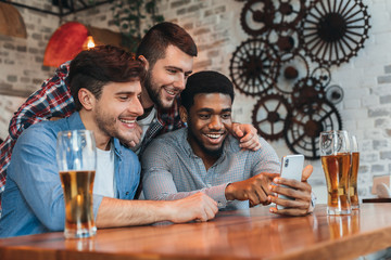 Old friends having fun with smartphone and drinking beer